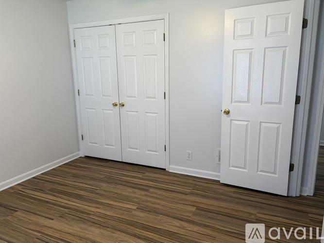 A room with two white doors and wooden flooring.