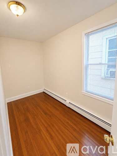 A room with wooden flooring and a window with blinds.