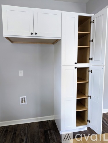 A white cabinet with open doors is in a room with a grey wall.