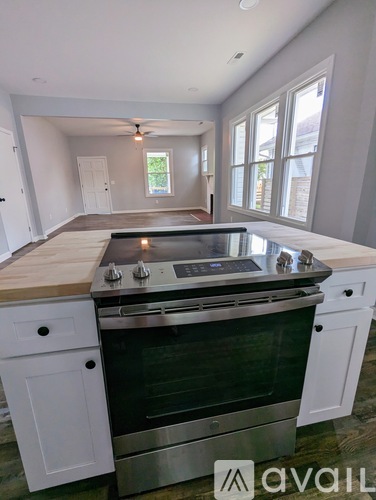 A kitchen with a stove top oven and white cabinets.