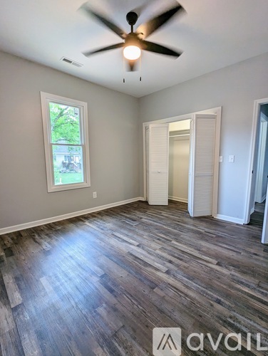 A room with a ceiling fan and a window with a view of trees.