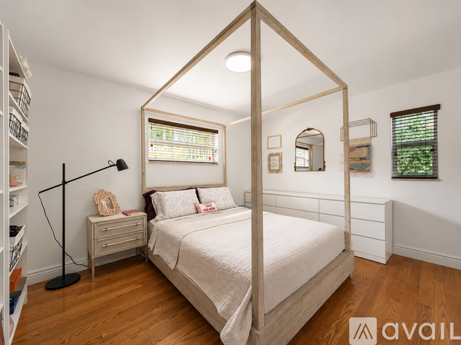 A bedroom with a four poster bed and a window with blinds.