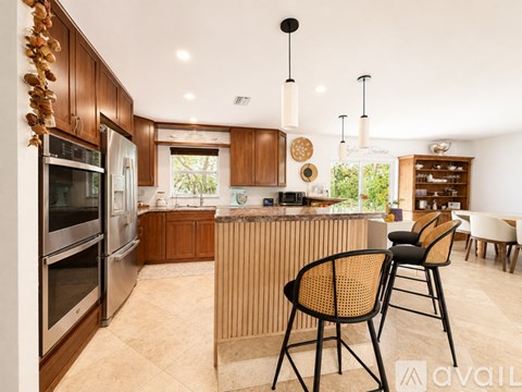 A kitchen with wooden cabinets and a large island with chairs.
