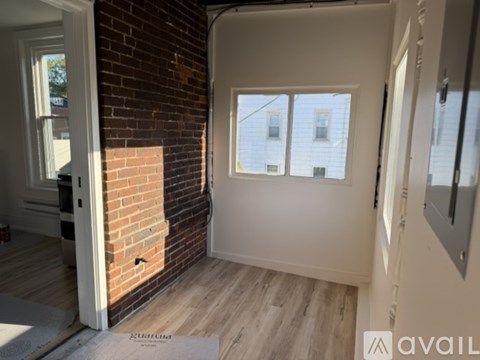 A room with a brick wall and a window overlooking a building.