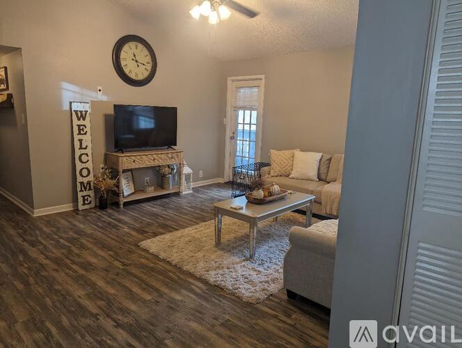 A living room with a wooden floor and a flat screen TV on a stand.