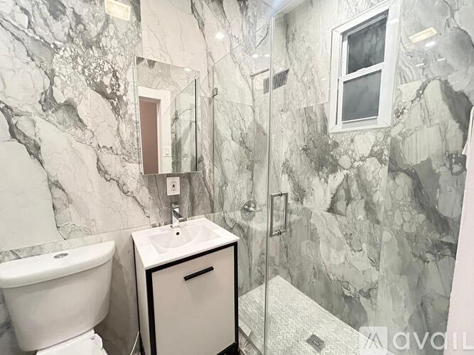 A bathroom with a marble wall and a white toilet.