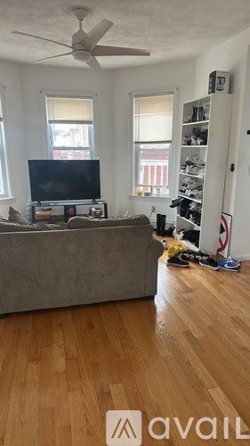 A living room with a grey couch and a television on a stand.