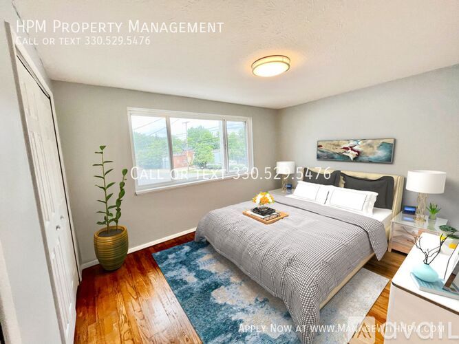 A bedroom with a bed, nightstand, and a plant in a vase.