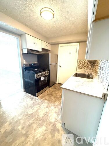 A kitchen with a black fridge and a white counter.