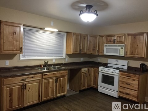 A kitchen with wooden cabinets and a white stove top oven.