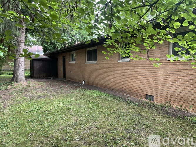 A house with a brown brick exterior and a tree in front.