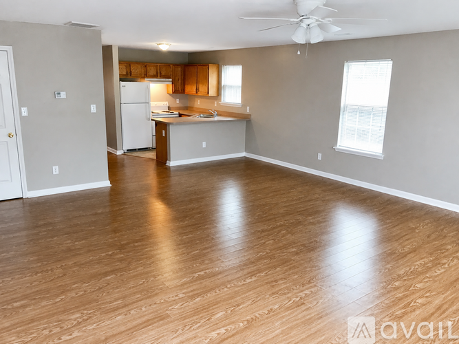 A spacious living room with a kitchen in the background.