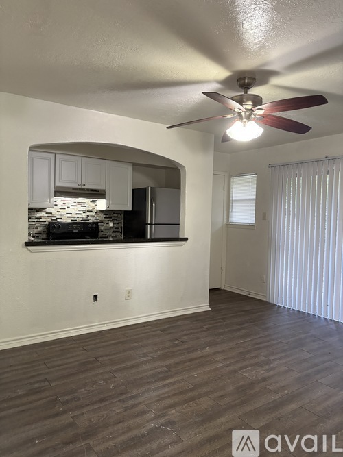 A room with a ceiling fan and wooden flooring.