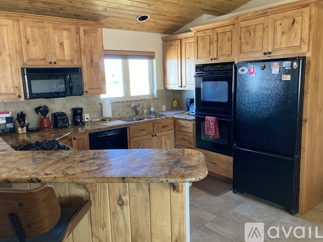 A kitchen with wooden cabinets and a black refrigerator.