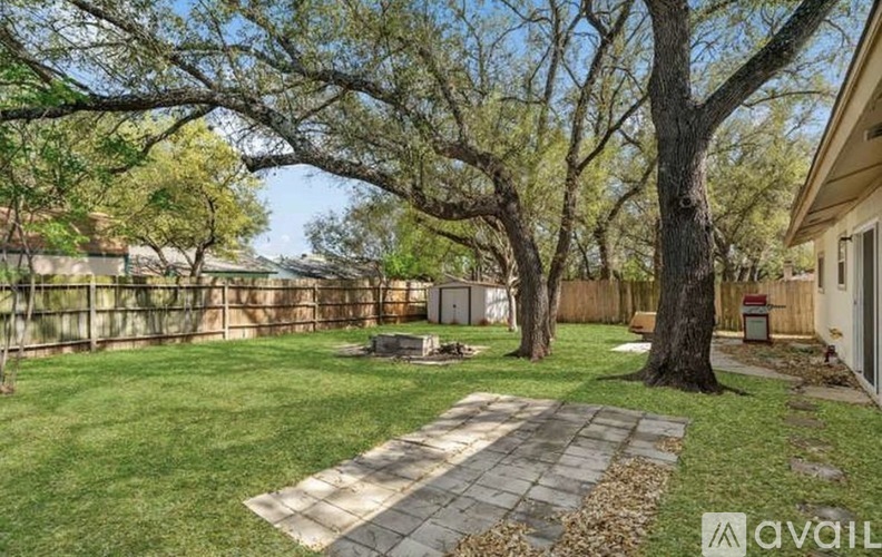 A backyard with a stone pathway, a tree, and a fence.