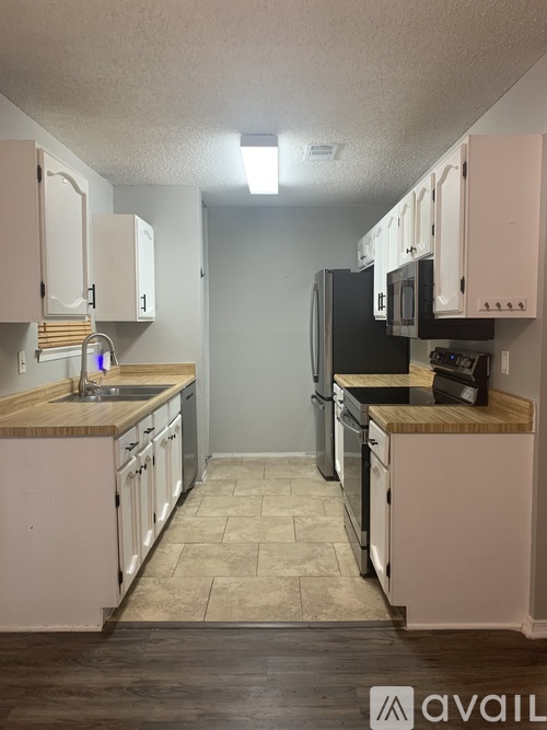 A kitchen with white cabinets and a black refrigerator.