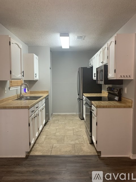 A kitchen with white cabinets and a black refrigerator.