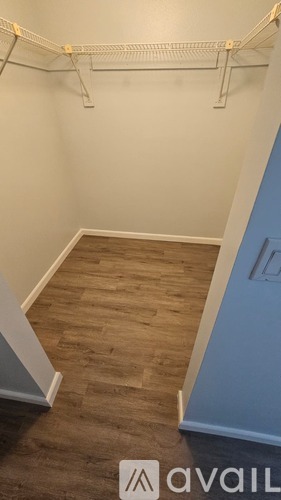 A room with a wooden floor and a white wall with a clothes rack.
