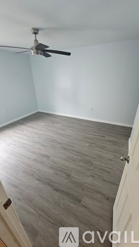 A room with a ceiling fan and wooden flooring.