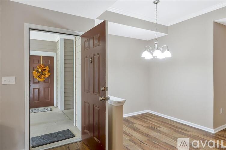 A room with a wooden floor and a door leading to a hallway.