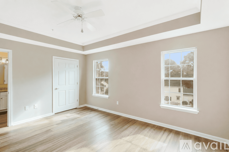 A spacious room with a ceiling fan and a window overlooking a building.