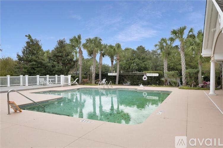 A pool surrounded by palm trees and deck chairs.