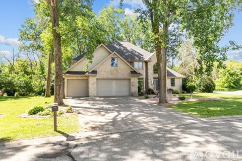 A house with a driveway and trees in front.