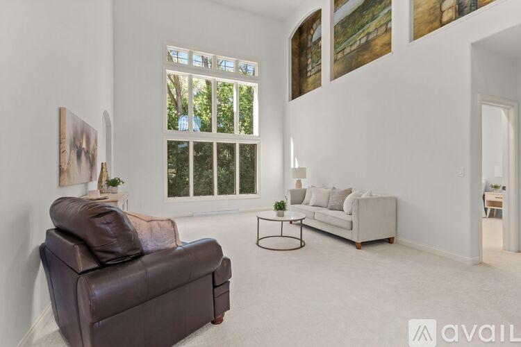 A living room with a brown leather couch, a white sofa, and a small table with a plant on it.