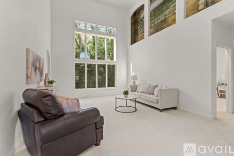 A living room with a brown leather couch, a white sofa, and a small table with a plant on it.