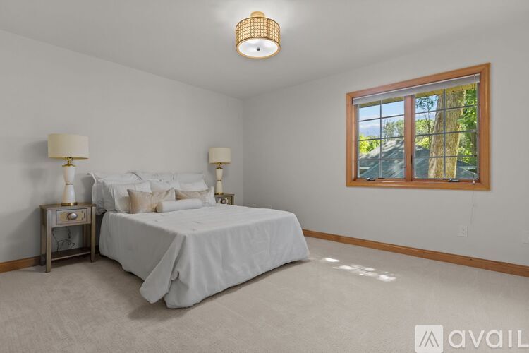 A bedroom with a large bed and two lamps.