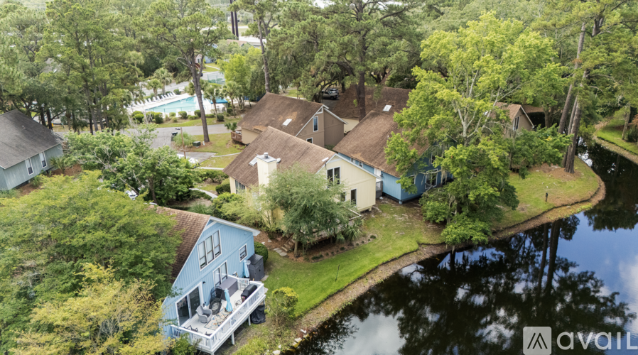 A bird's eye view of a house surrounded by trees and a body of water.