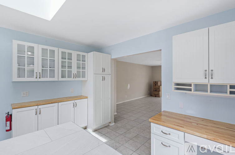 A kitchen with white cabinets and a wooden counter top.