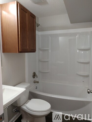 A white toilet sits under a cabinet in a bathroom.