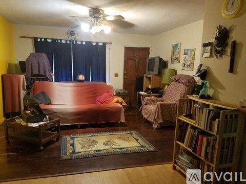 A living room with a red couch and a bookshelf.