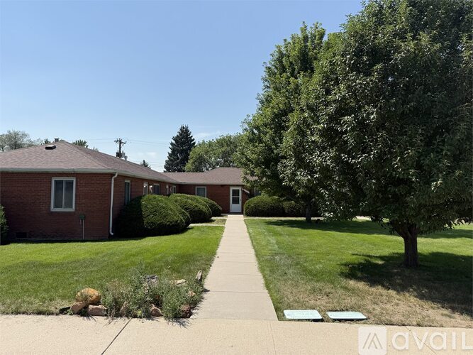 A house with a red brick exterior and a green lawn.