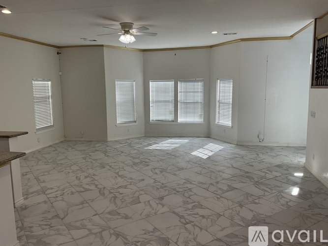 A spacious room with a marble floor and a ceiling fan.