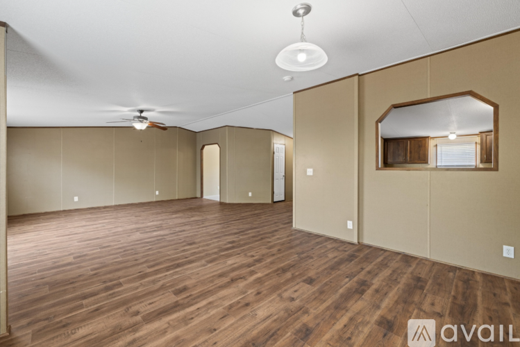 A spacious room with wooden flooring and a ceiling fan.