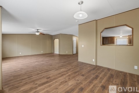 A spacious room with wooden flooring and a ceiling fan.