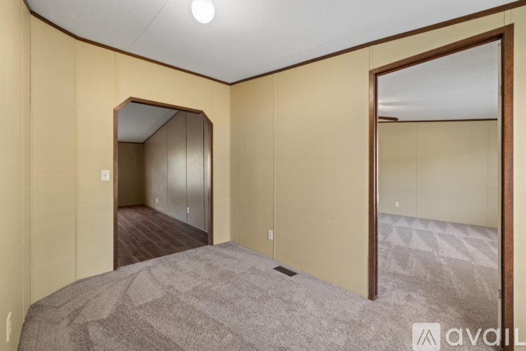 A bedroom with a carpeted floor and a large mirror on the wall.