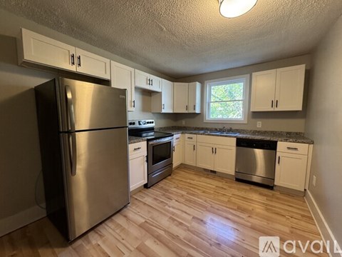 A kitchen with a stainless steel refrigerator and wooden floors.