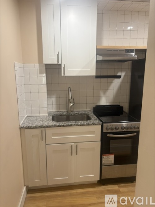 A kitchen with white cabinets and a black oven.