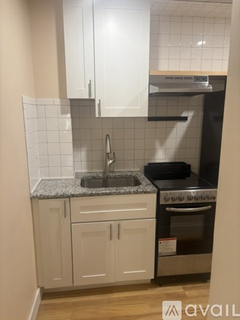 A kitchen with white cabinets and a black oven.