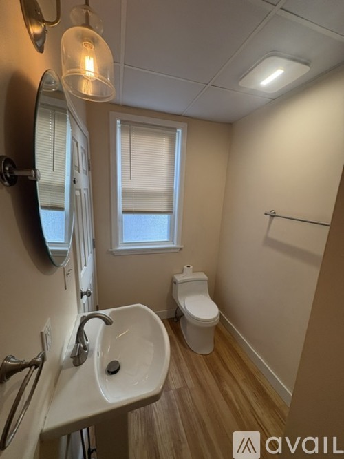 A bathroom with a sink, toilet, and a window with blinds.