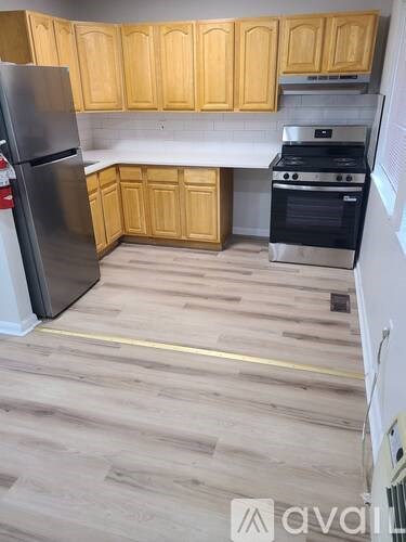 A kitchen with wooden cabinets and a stainless steel refrigerator.