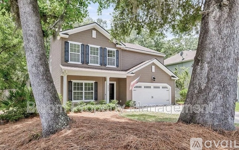 A house with a brown roof and a white garage door is surrounded by trees.