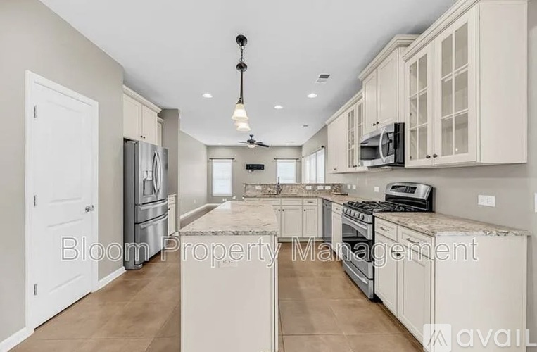 A spacious kitchen with white cabinets and appliances, and a text overlay that reads "Bloom Property Management".