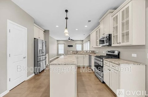 A spacious kitchen with white cabinets and appliances, and a text overlay that reads "Bloom Property Management".