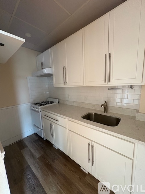 A kitchen with white cabinets and a marble countertop.