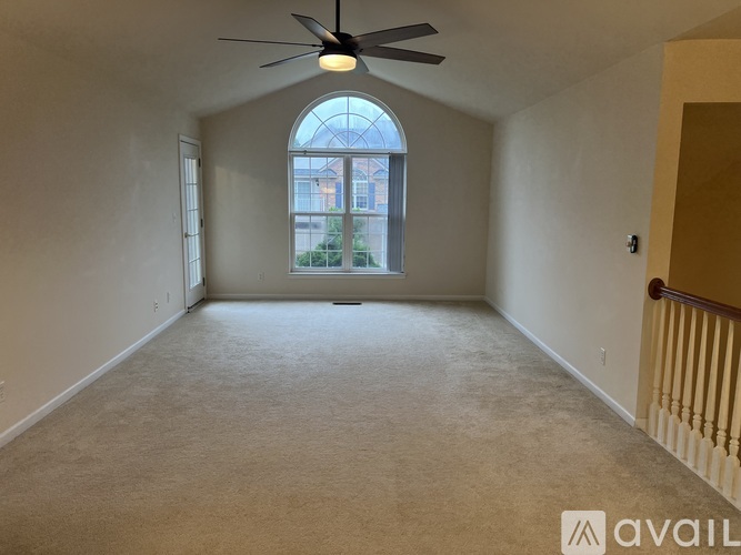 A spacious room with a ceiling fan and a large arched window.