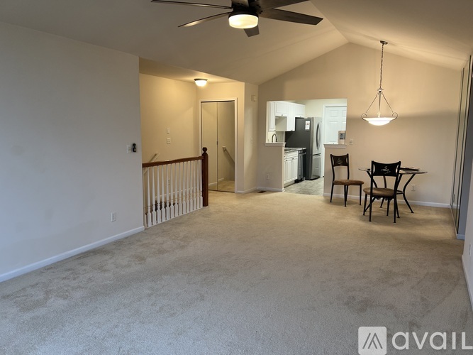 A spacious living room with a ceiling fan and a dining area in the background.